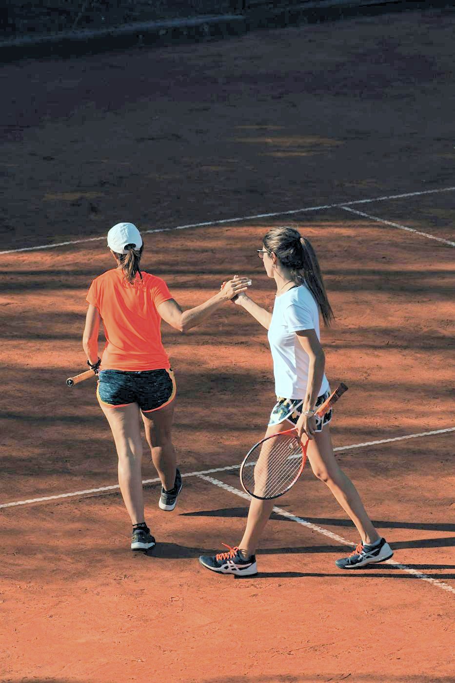 Two players high-fiving on court at sunset