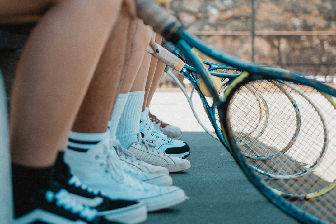 A team of players seated side by side, rackets lined up